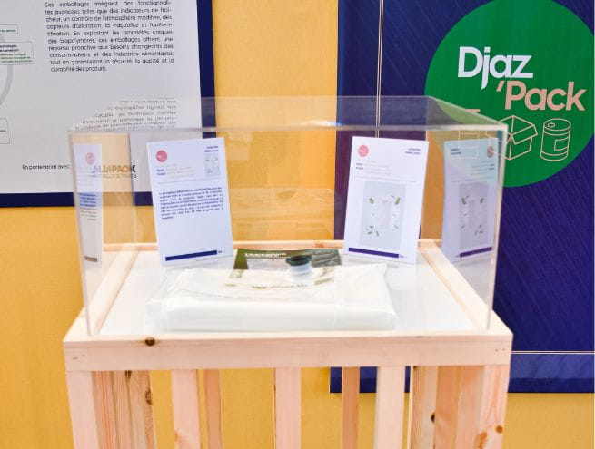 Présentation d'une innovation emballage dans l'espace Djaz'Pack, avec une vitrine en plexiglas contenant des prototypes et des fiches explicatives.