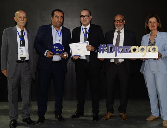 Groupe de professionnels en costume recevant un prix lors d’un événement, tenant un trophée et une pancarte #Djazagro